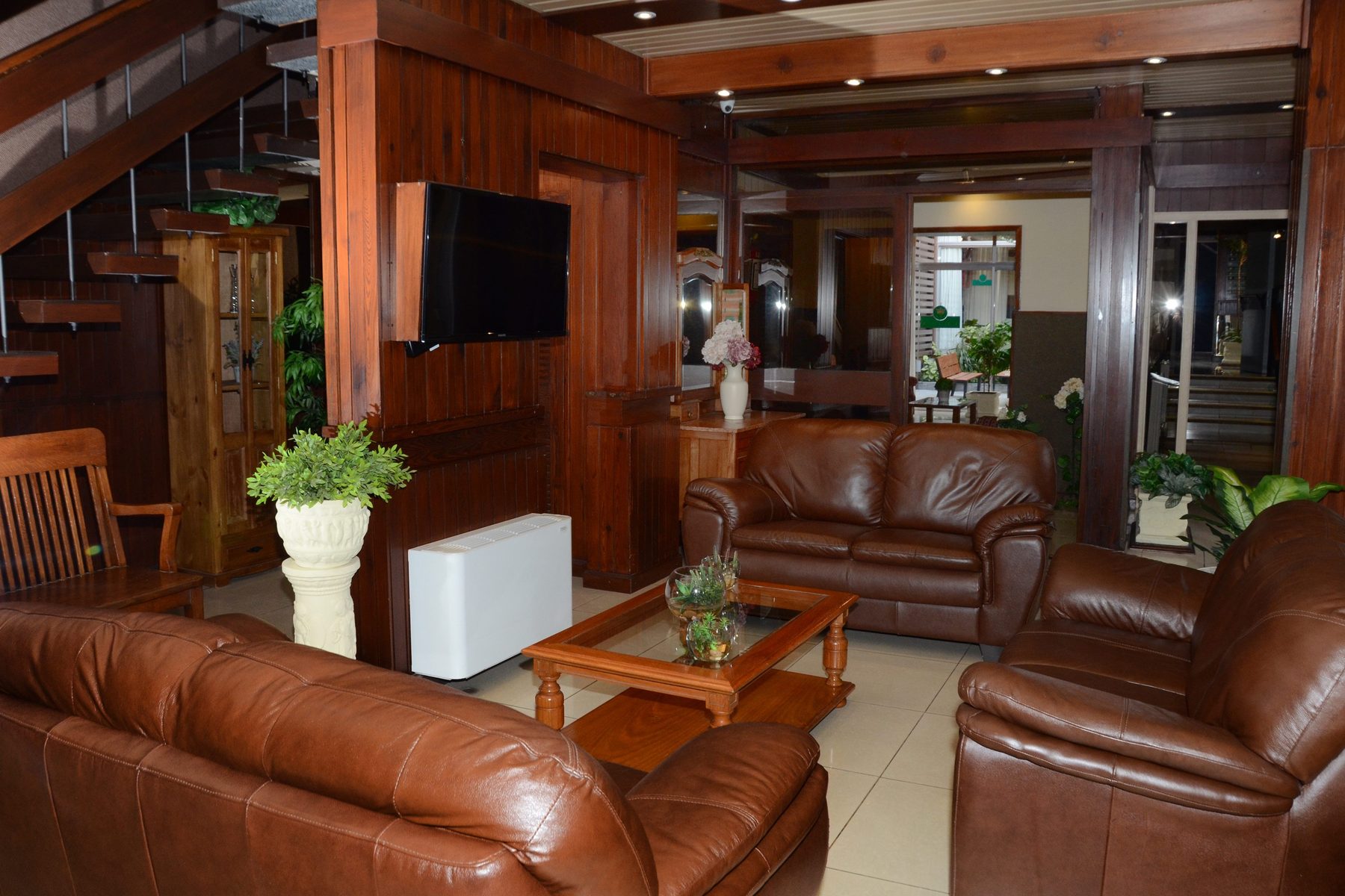 Estar con sillones de cuero marrón, televisor y boiserie de madera