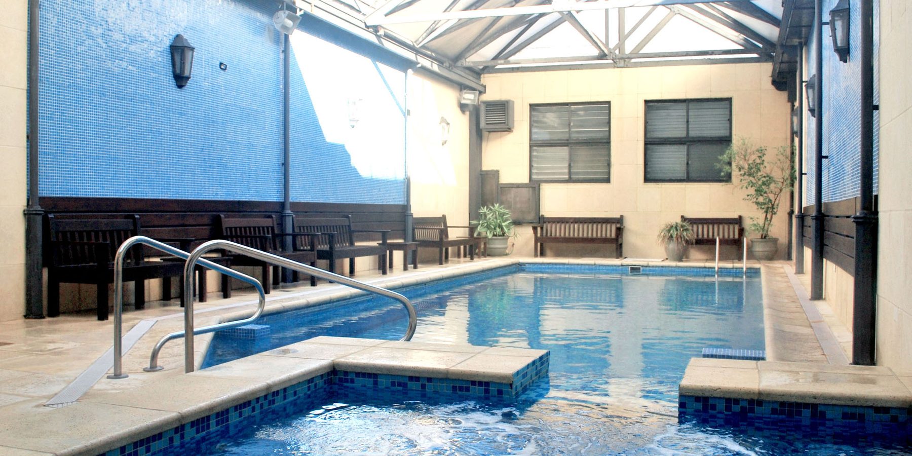 Piscina climatizada del Hotel Leoncia con el techo cerrado, la luz entra por las chapas translúcidas